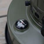 Close-up of a portable fire extinguisher pressure gauge on green surface.