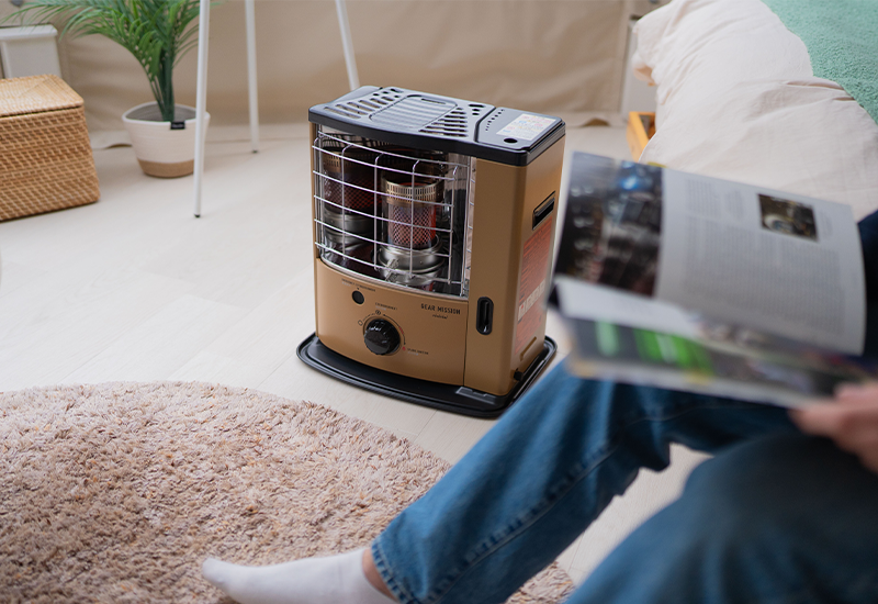 Toyotomi GEAR MISSION paraffin heater inside a glamping tent with a person reading a book