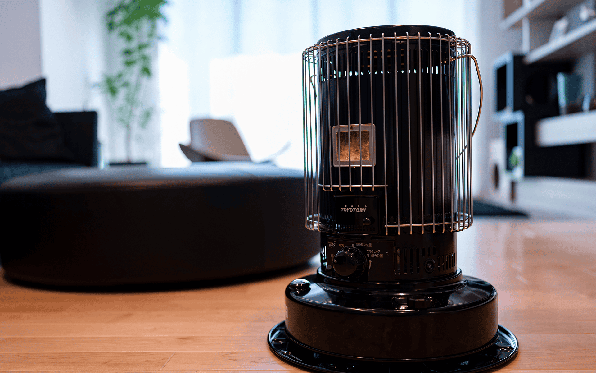 Image of a black Toyotomi space heater on a wooden floor, providing warmth in a modern, stylish living room.
