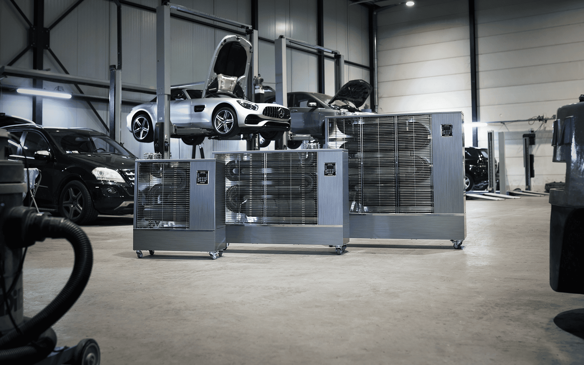 Automotive workshop featuring industrial heaters and high-end cars for servicing and maintenance.
